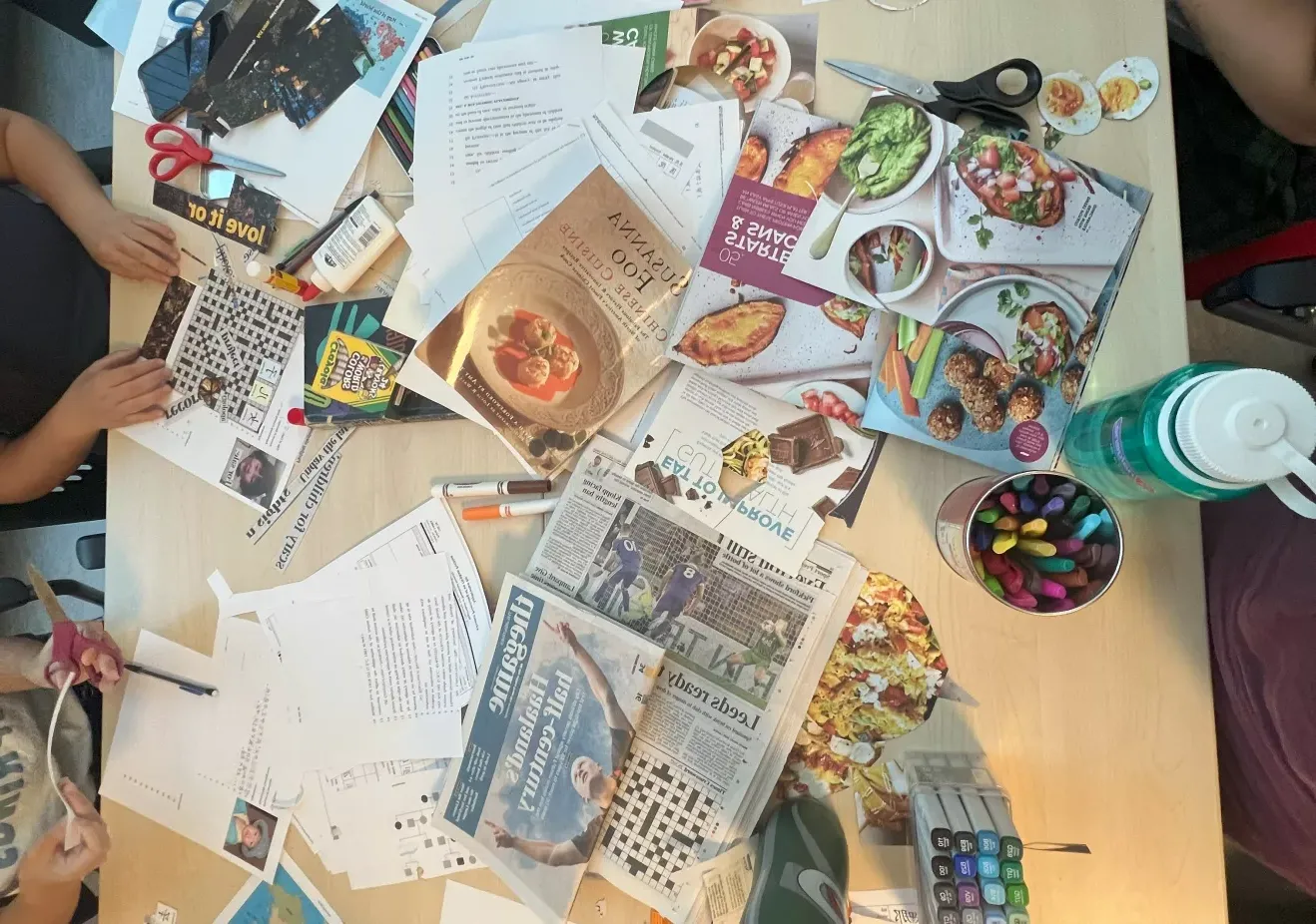 Table full of collage materials (magazine cutouts, pens, glue, etc.)